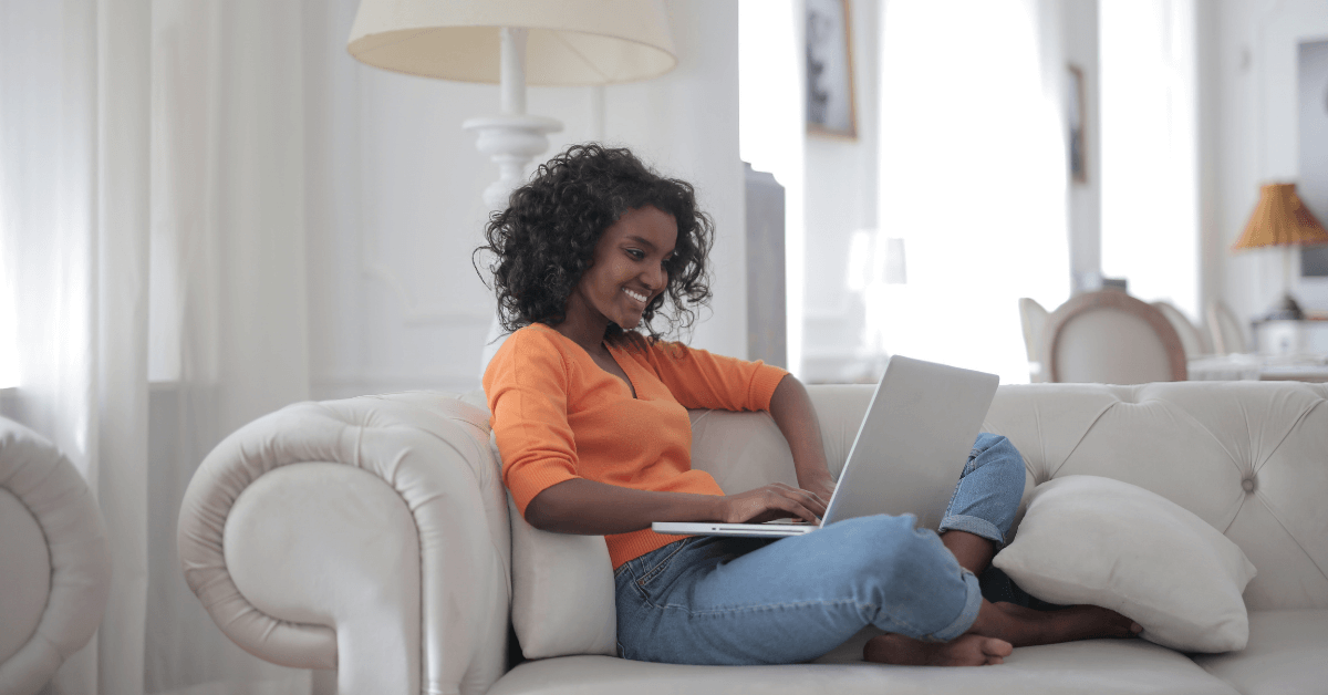Girl sitting on a couch researching furniture Ecommerce on a laptop
